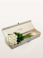 Coffret Chantilly ivoire ouvert, quinze roses blanches disposées sur papier de soie, logo René Veyrat visible
