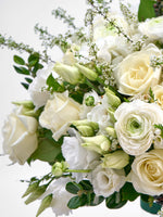 Roses ivoire, renoncules blanches, boutons de lisianthus verts et rameaux fleuris entremêlés