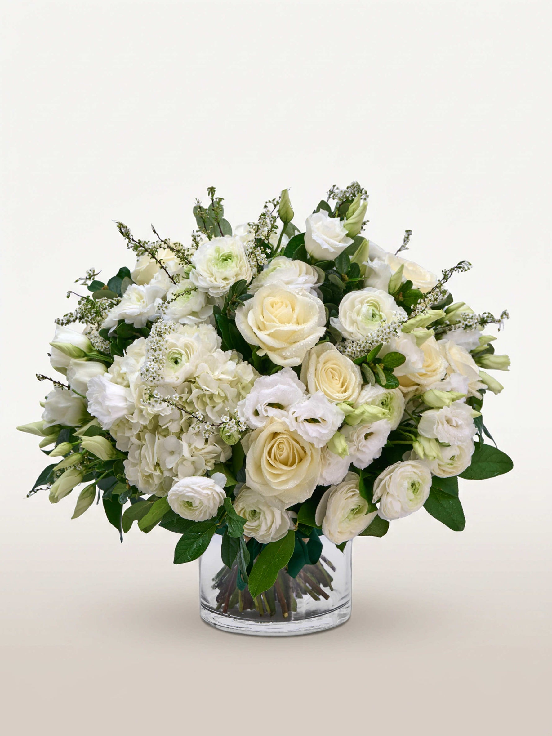 Reine Blanche M, roses et renoncules blanches, hortensias et feuillage vert dans un vase cylindrique en verre