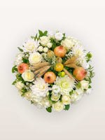 Roses blanches, dahlias, grenades entrouvertes et épis de blé disposés en cercle dense