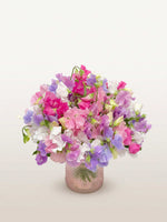 Bouquet Colibri de pois de senteur roses, blancs et mauves dans un vase en verre texturé rose