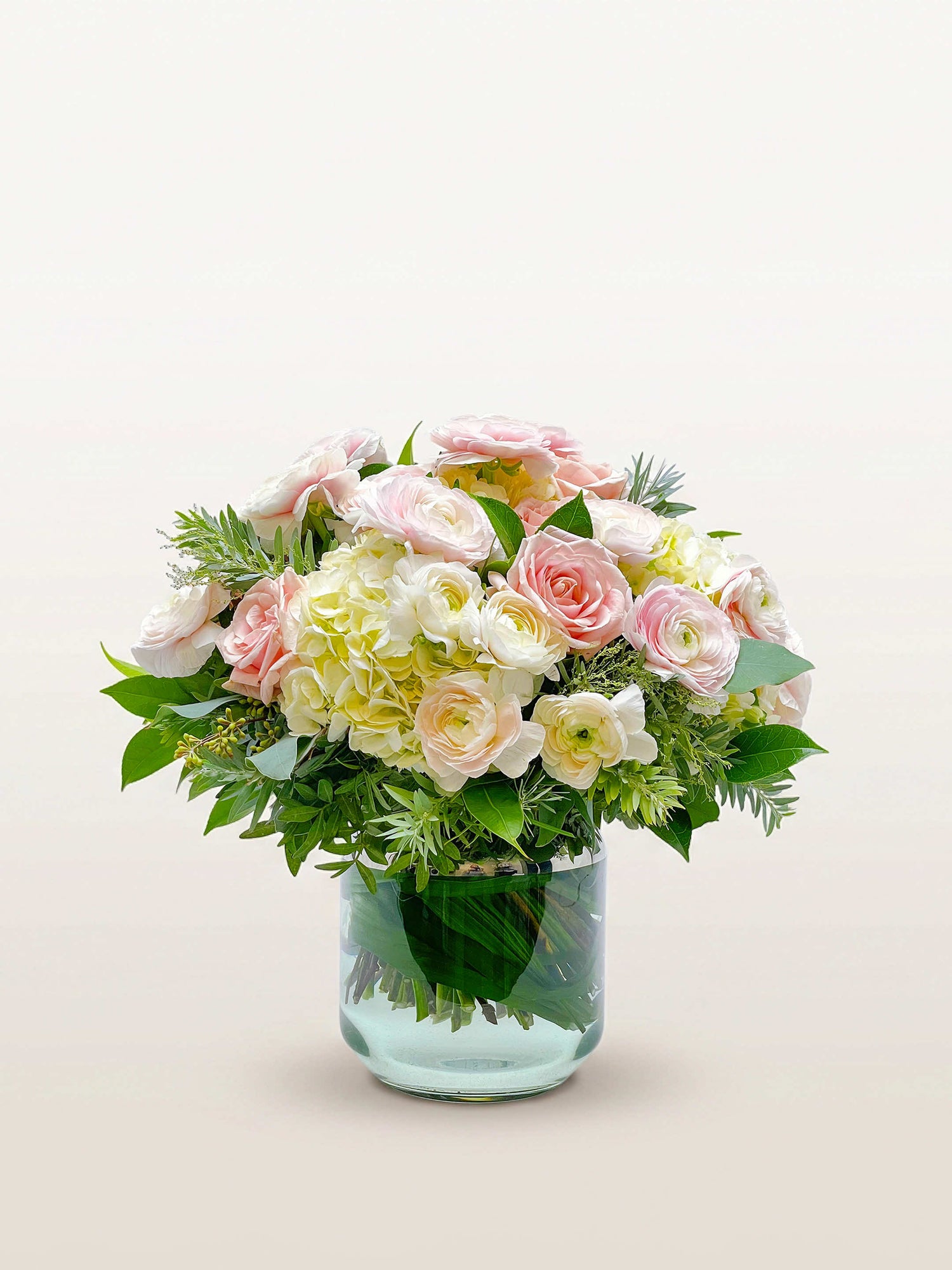 Championnet, roses roses et blanches, renoncules ivoire et hortensias, vase en verre transparent