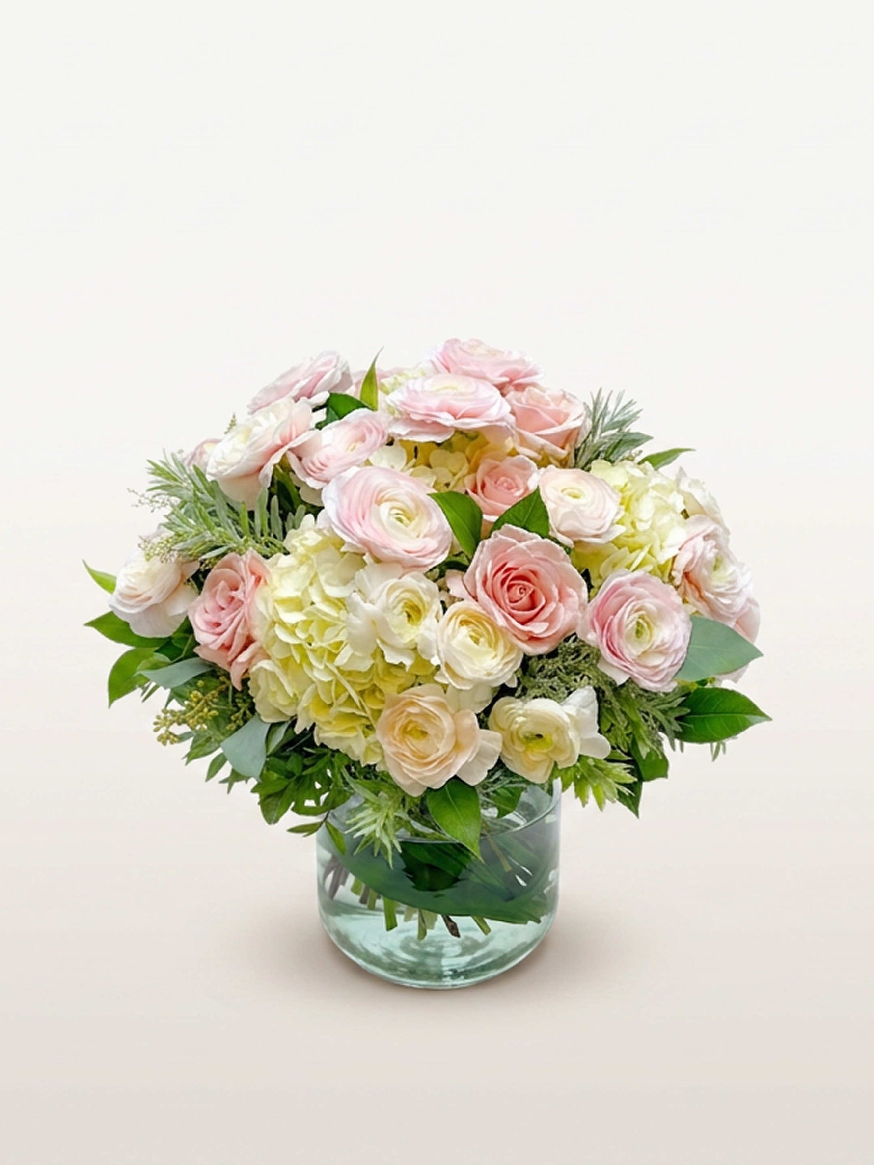 Championnet, roses roses et blanches, renoncules et hortensias blancs dans un vase en verre transparent