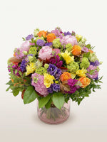 Oiseau de Paradis en bouquet rond XL, mêlant roses, pivoines et freesias multicolores dans un vase en verre