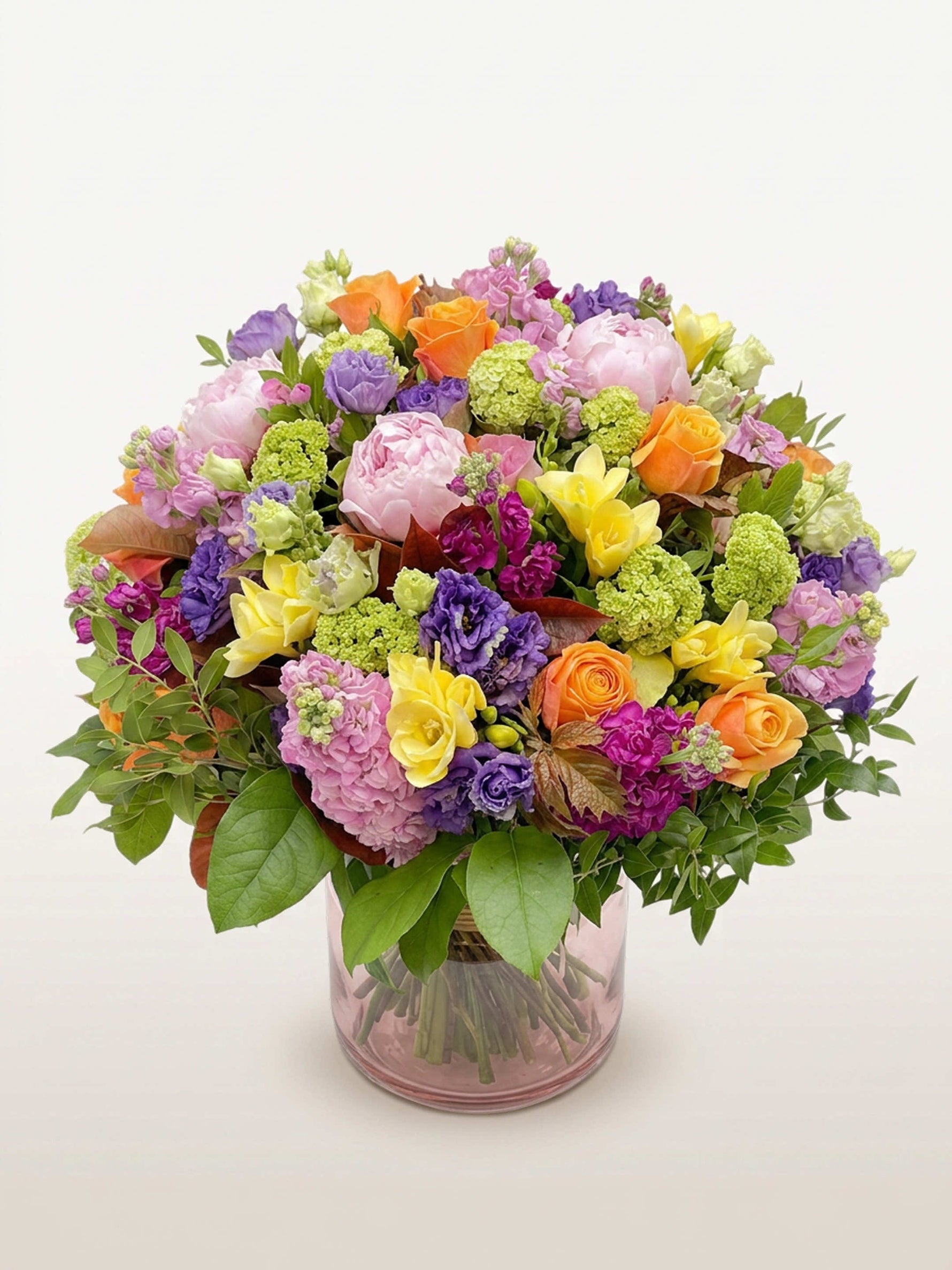 Oiseau de Paradis en bouquet rond XL, mêlant roses, pivoines et freesias multicolores dans un vase en verre