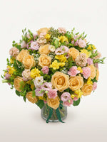 Point du Jour L, roses abricot, renoncules roses, lisianthus et freesias jaunes dans un vase en verre