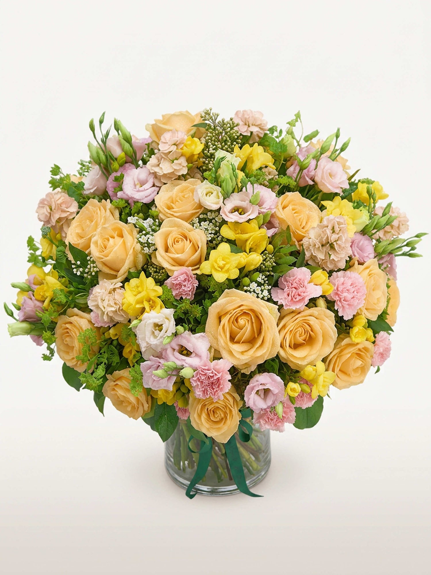 Point du Jour L, roses abricot, renoncules roses, lisianthus et freesias jaunes dans un vase en verre
