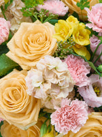 Point du Jour L, roses pêche, œillets roses, freesias jaunes et fleurs ivoire perlés de gouttes