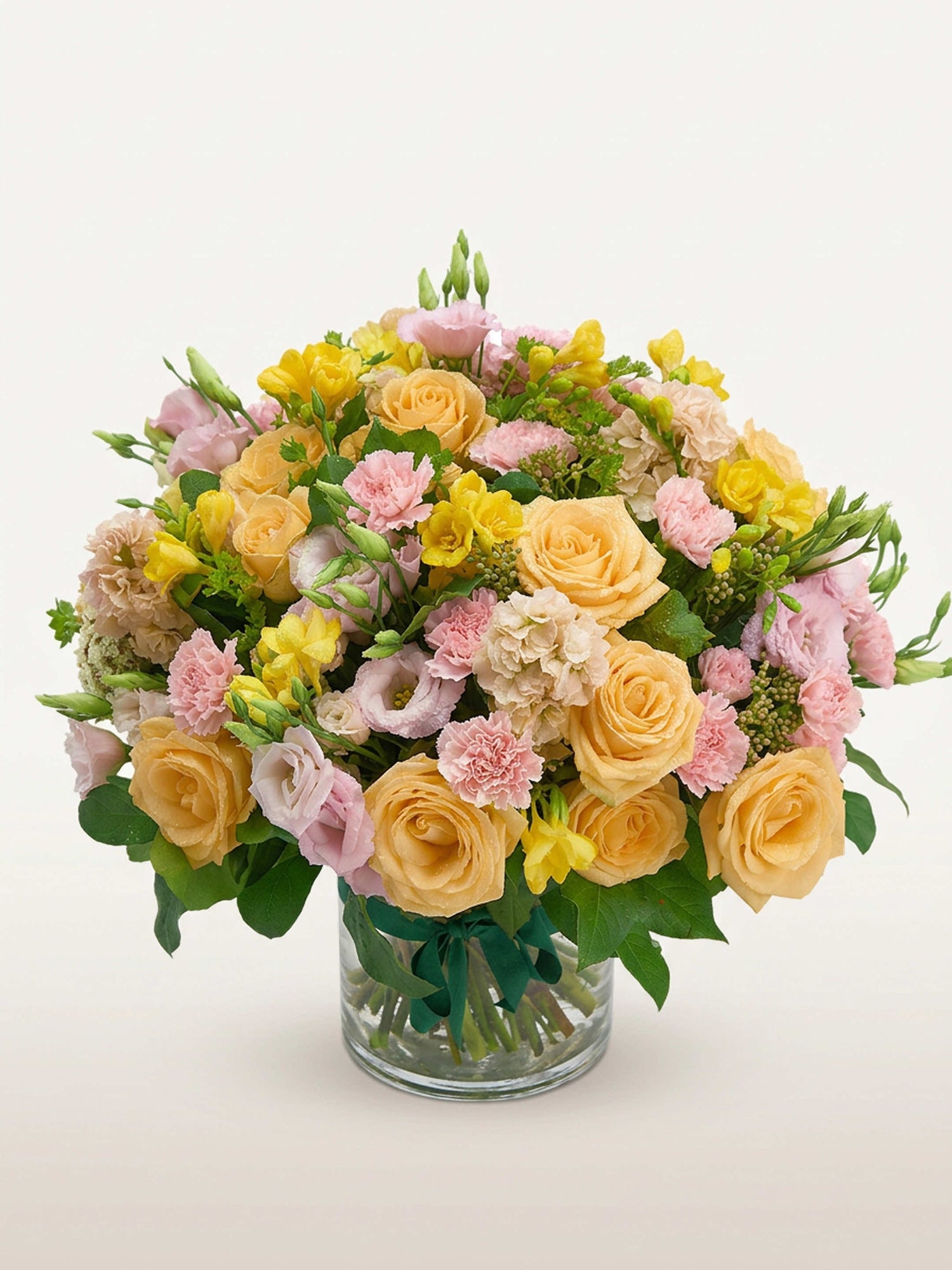Point du Jour M, roses abricot, œillets roses et renoncules blanches en bouquet rond dans un vase en verre