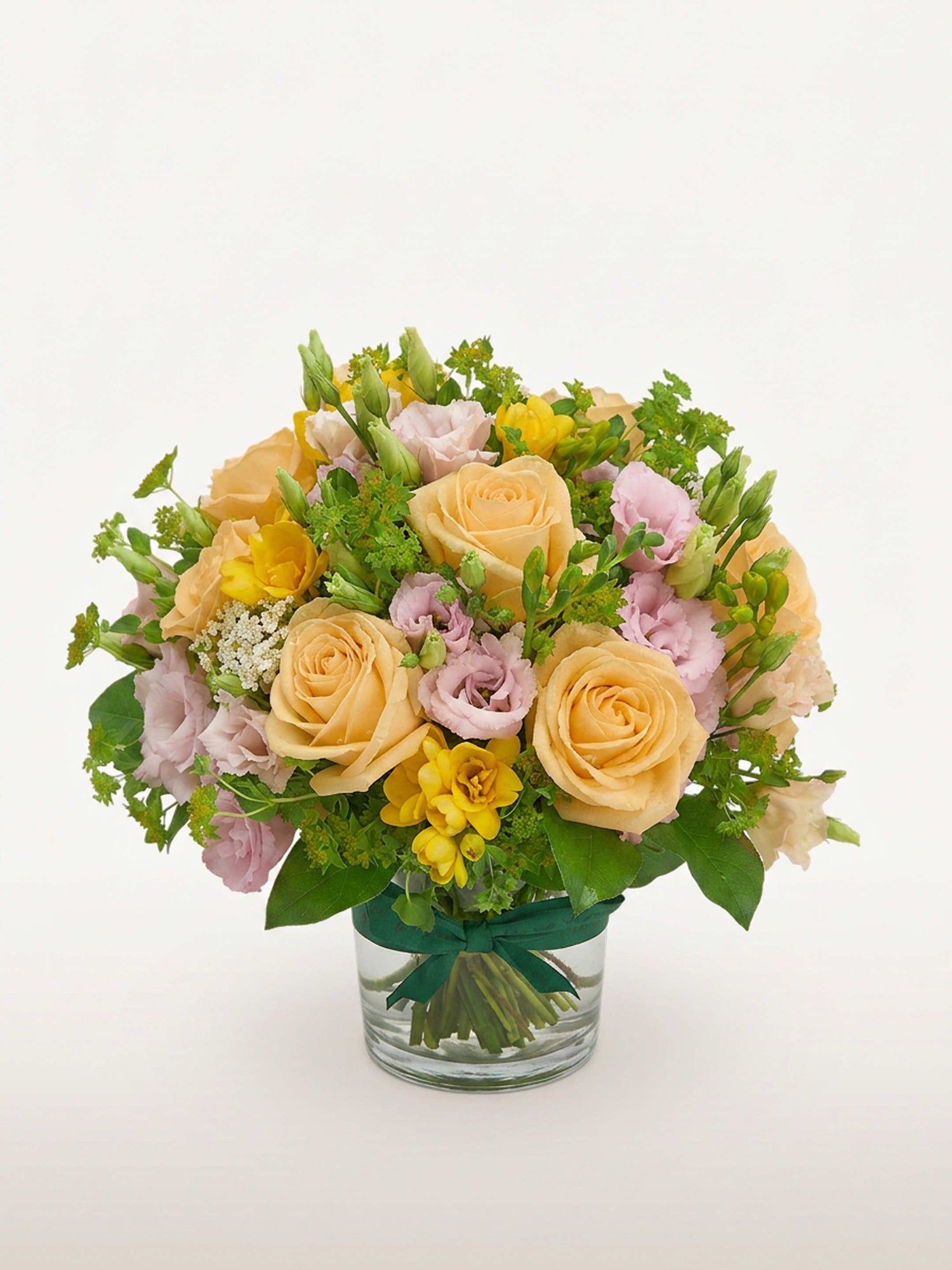 Point du Jour S, roses pêche, lisianthus roses, freesias jaunes et achillées blanches dans un vase en verre noué de ruban vert