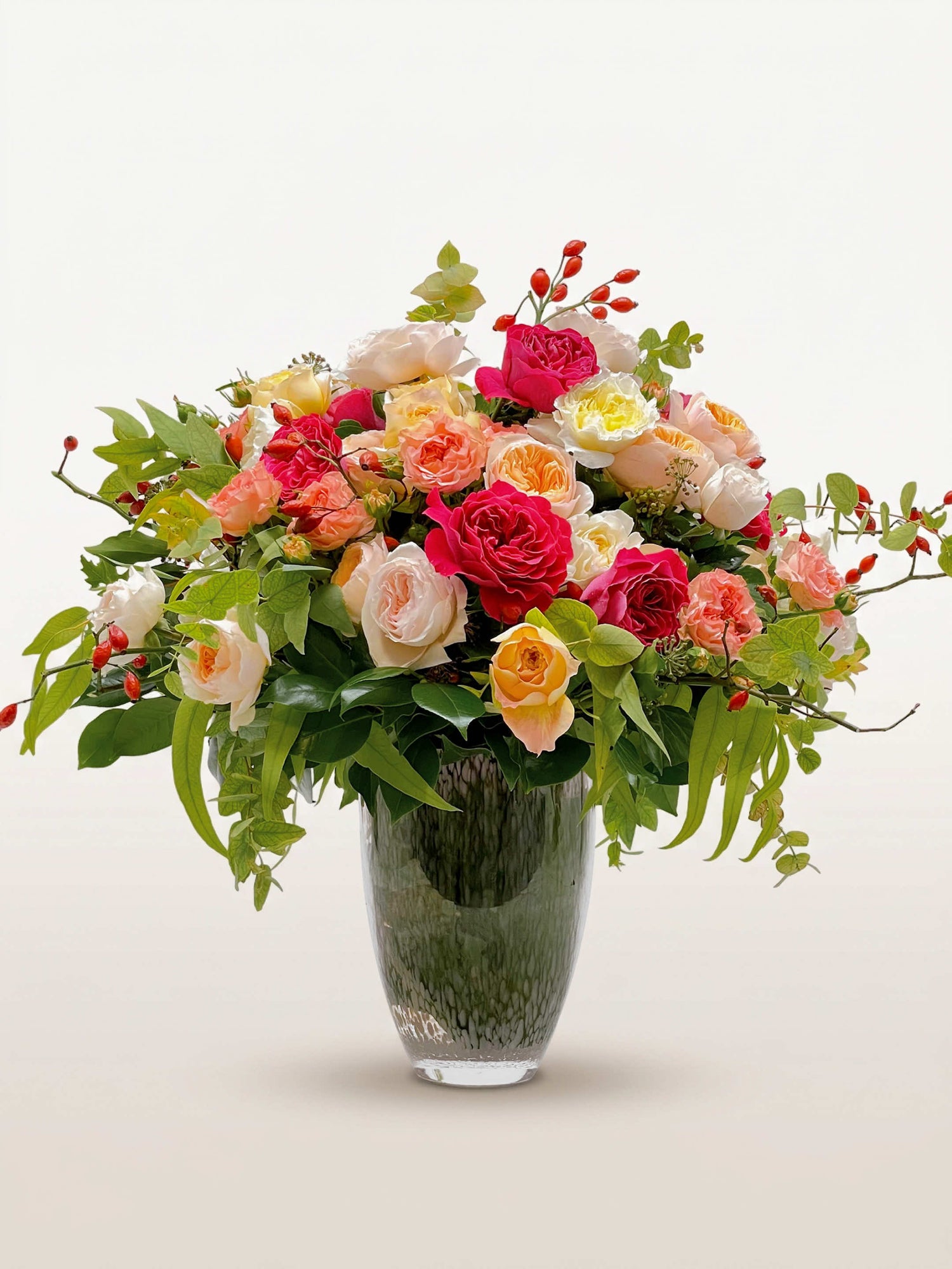 Rue de la Rosière, roses roses, blanches et fuchsia mêlées de fleurs d'églantier dans un vase en verre fumé