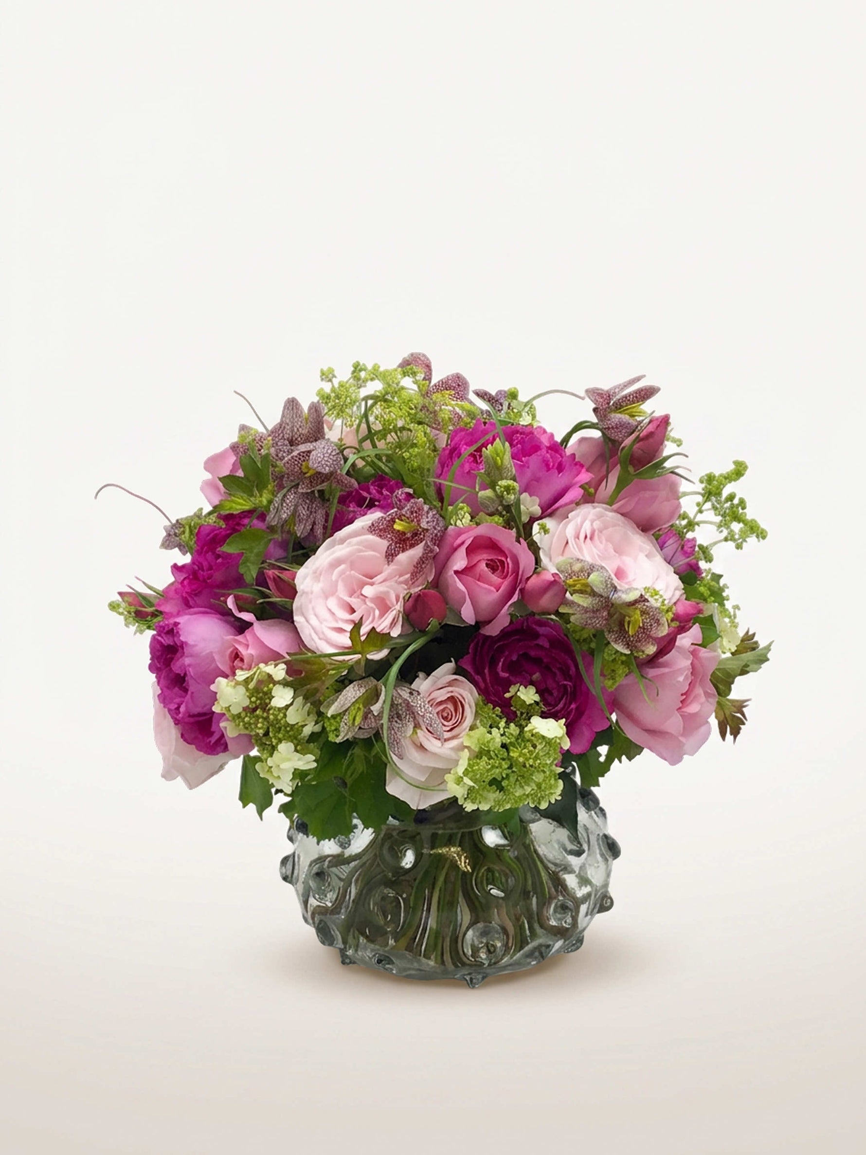 Parc Monceau, roses roses et pivoines fuchsia, fritillaires mouchetées et viornes vertes dans un vase gris texturé