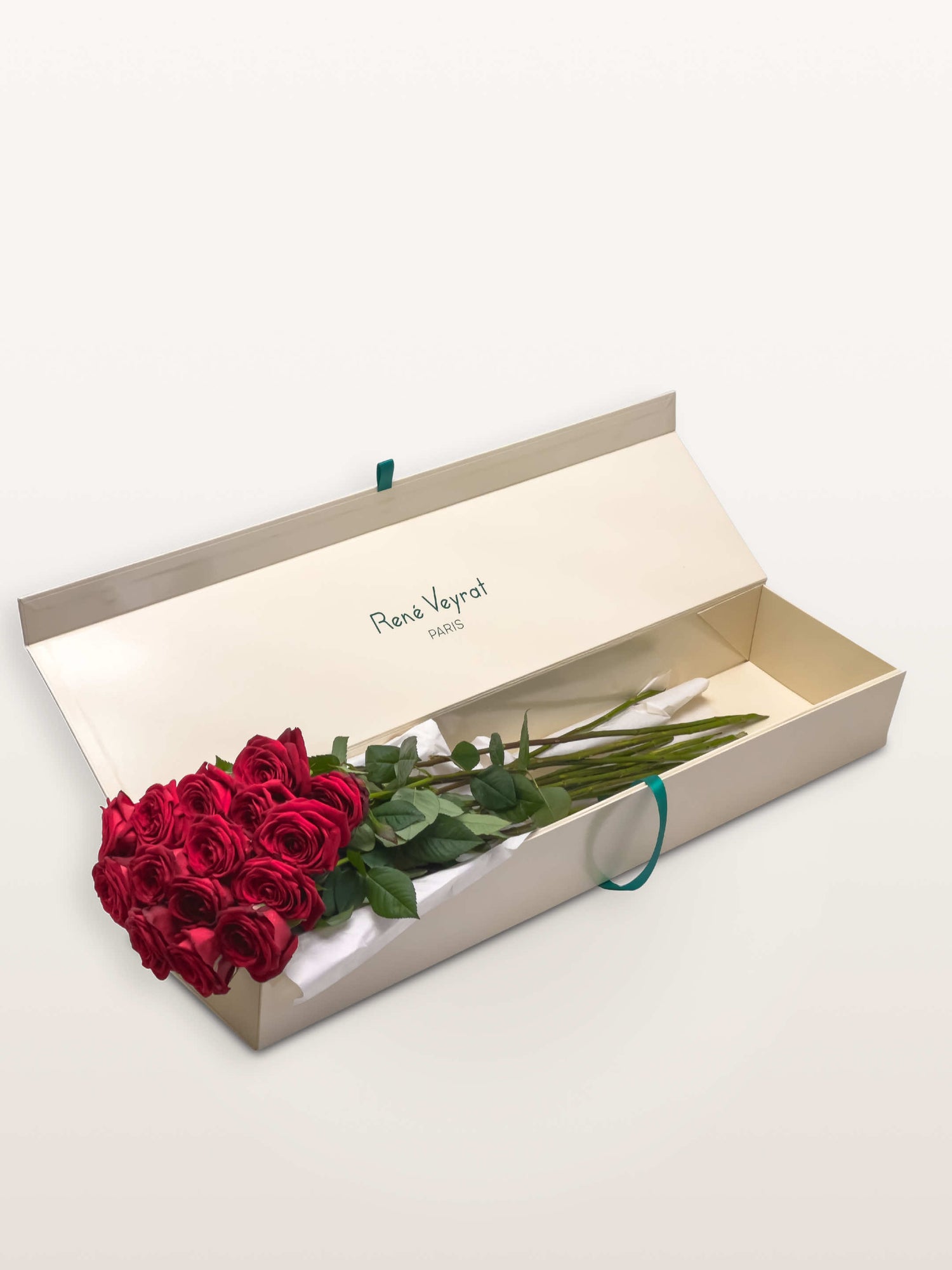 Coffret Royal ivoire ouvert, quinze roses rouges disposées sur papier de soie blanc, ruban vert émeraude