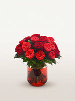 Cornaline, trente roses rouges en dôme rond dans un vase en verre teinté orangé