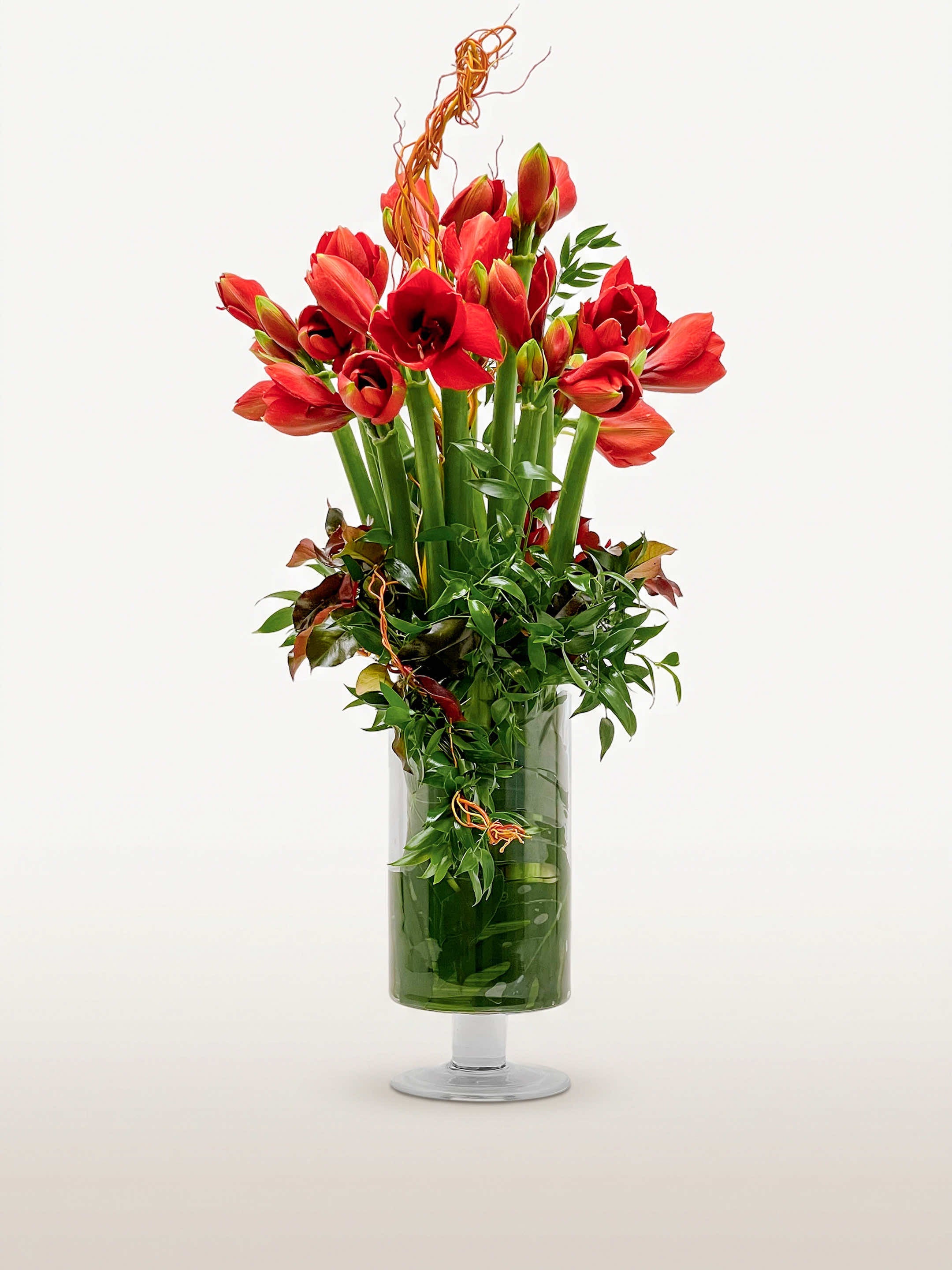 Porte de Montrouge L, bouquet graphique d'amaryllis rouges et tulipes écarlates rehaussé de courbes végétales, dans un vase cylindrique sur pied