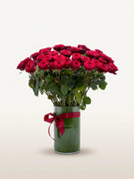 Royal N°75 dévoile une brassée XL de roses rouge velouté dans un vase cylindrique noué d'un ruban carmin
